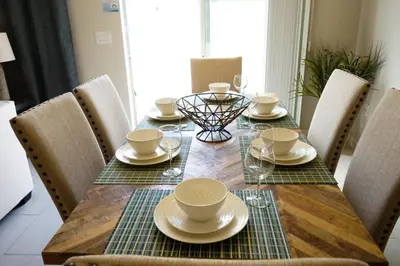 a dining room table with chairs and a table with plates and cups at Special Offer Townhome at Compass Bay in Kissimmee