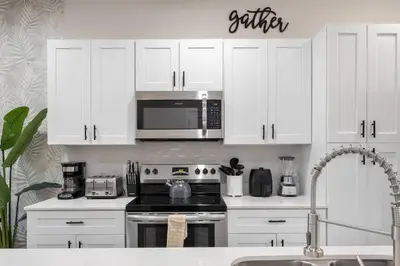 a kitchen with white cabinets and a stove and a microwave at New Listing - Modern decoration 4 BR Townhouse in Kissimmee