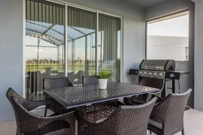 a table and chairs on a balcony with a grill at Casa Luxuosa 5Q c/ Piscina Perto da Disney! in Kissimmee