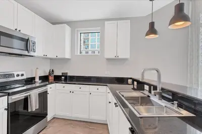 a kitchen with white cabinets and a sink at Modern 3 bedroom condo in downtown w free parking in Orlando