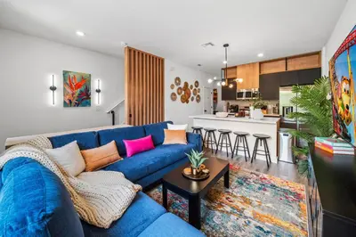 a living room with a blue couch and a kitchen at Colorful vibrant Oasis Sleeps 10, 10min to Disney in Kissimmee