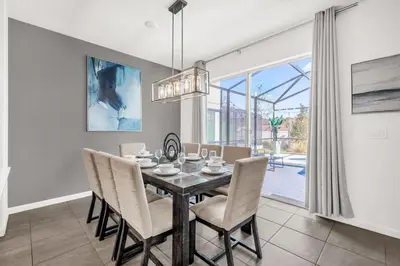 a dining room with a table and chairs and a window at Upstay Vibrant Home w Themed Rooms Pool & Games in Kissimmee