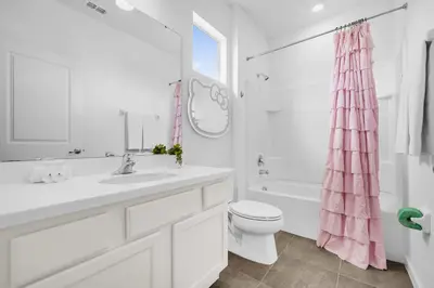 a white bathroom with a sink and a toilet at Upstay Vibrant Home w Themed Rooms Pool & Games in Kissimmee