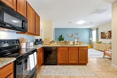a kitchen with wooden cabinets and a stove top oven at 5BR Disney Villa with Private Pool & Spa in Kissimmee