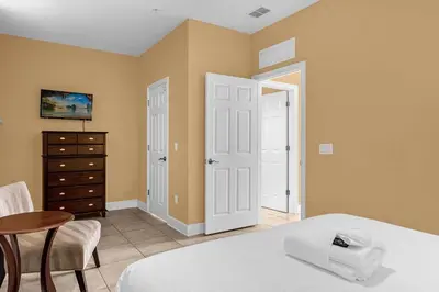 a bedroom with a bed and a table and a chair at Sunny Sales - Renovated TownHome by Disney! in Orlando