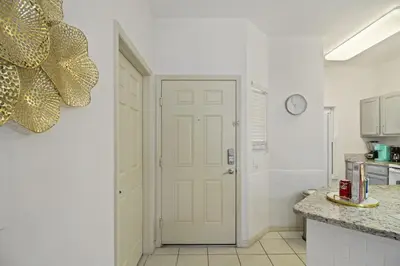 a kitchen with a white door and a clock on the wall at Cozy 3bd Townhouse Near Disney Encantada Resort in Kissimmee
