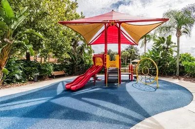 a playground with a red slide and an umbrella at Cozy 3bd Townhouse Near Disney Encantada Resort in Kissimmee
