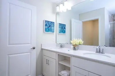 a white bathroom with two sinks and a mirror at Gorgeous 2Bd Close to Disney at Storey Lake Resort in Kissimmee