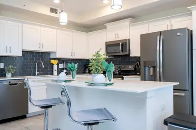 a kitchen with white cabinets and a stainless steel refrigerator at Family Condo 2Bd Close to Disney at Storey Lake Resort in Kissimmee