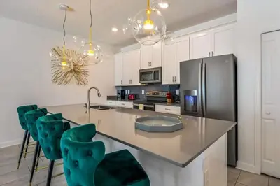 a kitchen with a stainless steel refrigerator and green chairs at Casa com Piscina Privativa a 10 Min da Disney in Kissimmee