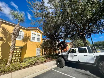 a white truck parked in front of a yellow house at Grand Emerald 3BR Townhouse Near Disney Parks in Kissimmee