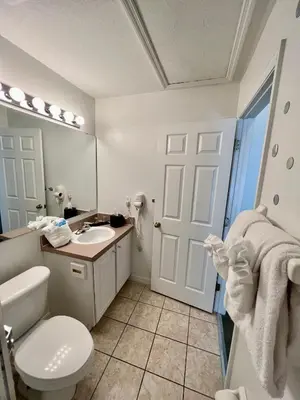 a bathroom with a toilet and a sink and a mirror at Grand Emerald 3BR Townhouse Near Disney Parks in Kissimmee