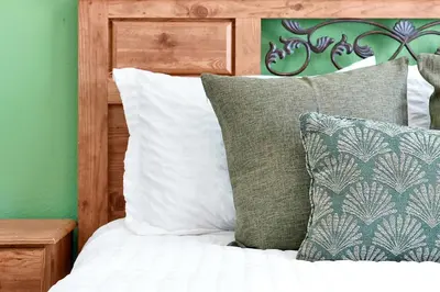 a bed with green and white pillows and a wooden headboard at 5BR Cottage w Pool & Hot Tub Near Disney in Kissimmee