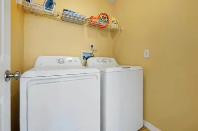 a laundry room with a white refrigerator and shelves at 5BR Cottage w Pool & Hot Tub Near Disney in Kissimmee