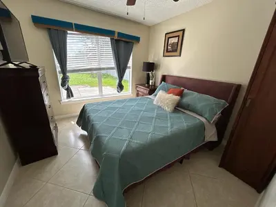 a bedroom with a bed with a blue comforter and a window at Orlando Family 4BR | 10 Min to SeaWorld in Orlando