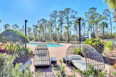 a patio with two chairs and a pool at Modern Pet-Friendly - 2BR Condo - 6 mins from Disney in Orlando