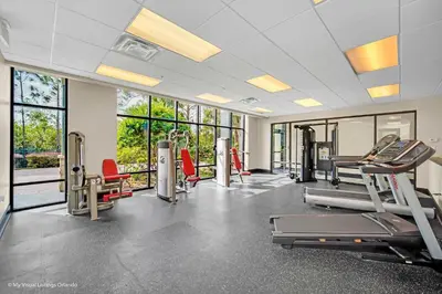 a gym with treadmills and ellipticals and windows at Modern Pet-Friendly - 2BR Condo - 6 mins from Disney in Orlando