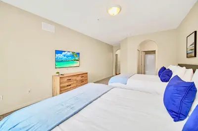 two beds in a bedroom with white walls and blue pillows at Stylish 2BR Retreat w Pool Sauna in Orlando