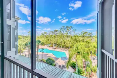 a balcony with a view of a pool and palm trees at Stylish 2BR Retreat w Pool Sauna in Orlando