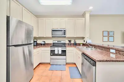 a kitchen with white cabinets and a stainless steel refrigerator at Stylish 2BR Retreat w Pool Sauna in Orlando