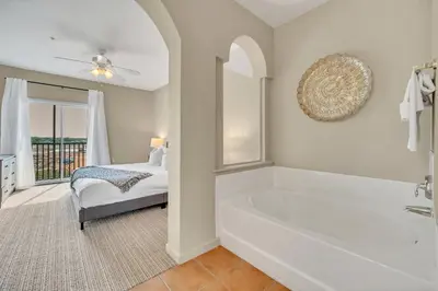 a white bathroom with a tub and a bed at Upstay - Condo - Hot Tub & Pool in Orlando