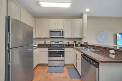 a kitchen with white cabinets and a stainless steel refrigerator at Upstay - Condo - Hot Tub & Pool in Orlando