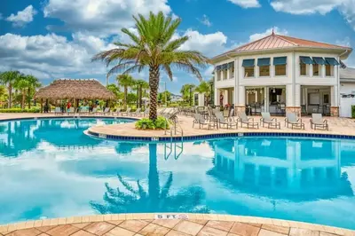 a resort pool with chairs and palm trees at Casa 6 Quartos | Piscina Privativa | 10min Disney! in Kissimmee