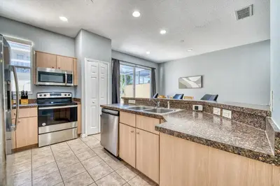 a kitchen with stainless steel appliances and wooden cabinets at Stylish Townhome Close to Disney Parks in Kissimmee