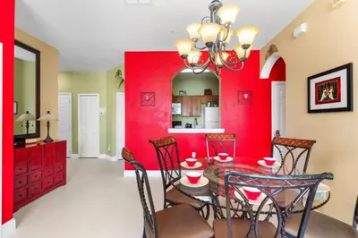 a dining room with red walls and a table with chairs at Windsor Palms Mickey Themed Condo, Pool, By Disney in Kissimmee