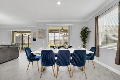 a dining room with a white table and blue chairs at Disney Nearby! Private Pool, Movie Theater & Themed Rooms – Storey Lake Resort! in Kissimmee