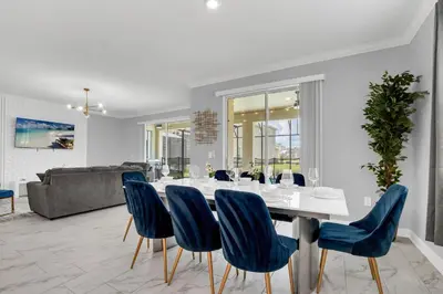 a dining room with a white table and blue chairs at Disney Nearby! Private Pool, Movie Theater & Themed Rooms – Storey Lake Resort! in Kissimmee