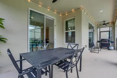 a wooden table and chairs in a patio with lights at Disney Nearby! Private Pool, Movie Theater & Themed Rooms – Storey Lake Resort! in Kissimmee
