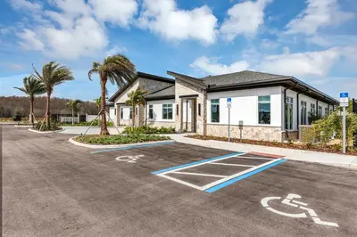 a parking lot in front of a building with palm trees at Dream Vacation Home – Private Pool, Themed Rooms & Resort Access – ChampionsGate! in Kissimmee