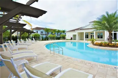 a swimming pool with white chairs next to a house at Dluxx Perfect Townhouse next to Disney Parks 3204 in Kissimmee