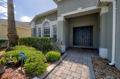 a house with a driveway and a door with bushes at Private Pool Getaway Near Theme Parks in Kissimmee