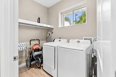 a small laundry room with two washes and a stroller at Home Luxury 4 BedsPrivate Hot Tub Close Disney in Orlando