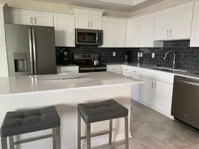 a kitchen with white cabinets and a large island with stools at Aqua Vista Storey Lake in Kissimmee
