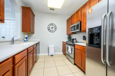 a kitchen with wooden cabinets and a stainless steel refrigerator at Epic Universe New Listing Beautiful Vacation Condo - 3018 in Orlando