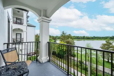 a balcony with a chair and a view of a river at Epic Universe Beautiful Lakeview Condo, Vista Cay Orlando - 3013 in Orlando