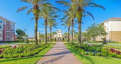 a pathway with palm trees in front of a building at New - Lakeview Vacation Condo - 3027 in Orlando
