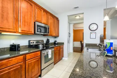 a kitchen with wooden cabinets and a stove top oven at Epic Universe NEW Beautiful Lakeview Condo Near the Parks - 1026 in Orlando