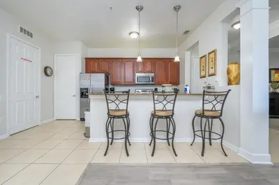 a kitchen with three bar stools and a counter at Epic Universe Condo-Vista Cay - 2022 in Orlando