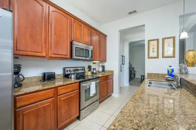 a kitchen with wooden cabinets and a stove top oven at Epic Universe Condo-Vista Cay - 2022 in Orlando
