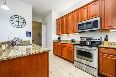 a kitchen with wooden cabinets and a stove and microwave at Epic Universe Penthouse Vacation Condo, Near the Parks - 2014 in Orlando