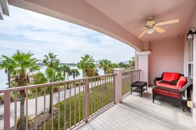 a balcony with a view of the water and palm trees at Epic Universe Premium Lake View Condo, Vista Cay - 1002 in Orlando