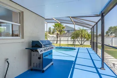 a grill on a patio next to a swimming pool at Villa Resort Club in Kissimmee
