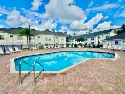 a swimming pool in a courtyard with chairs and buildings at Grand Laguna 3BR Penthouse Near Disney Parks in Kissimmee