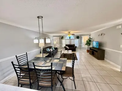 a dining room and living room with a table and chairs at Grand Laguna 3BR Penthouse Near Disney Parks in Kissimmee