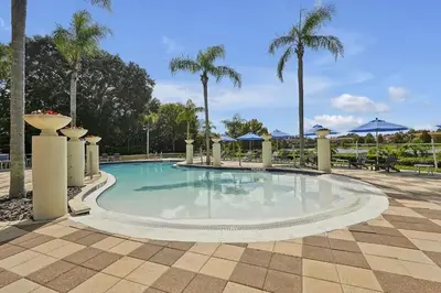 a large swimming pool with palm trees and umbrellas at Encantada Resort 10 minutes to Disney w/ Pool in Kissimmee