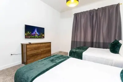 a bedroom with two beds and a tv and a dresser at Casa 5Q c/ Piscina e Temas da Disney in Kissimmee